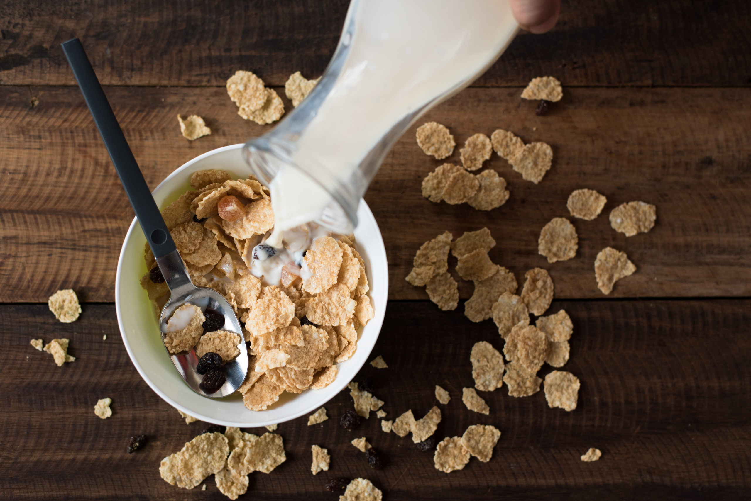 Pouring milk on cereal.