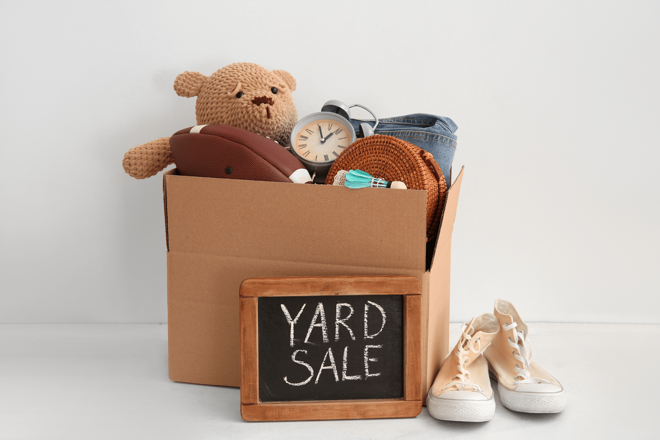 Yard sale with shoes by a cardboard box.