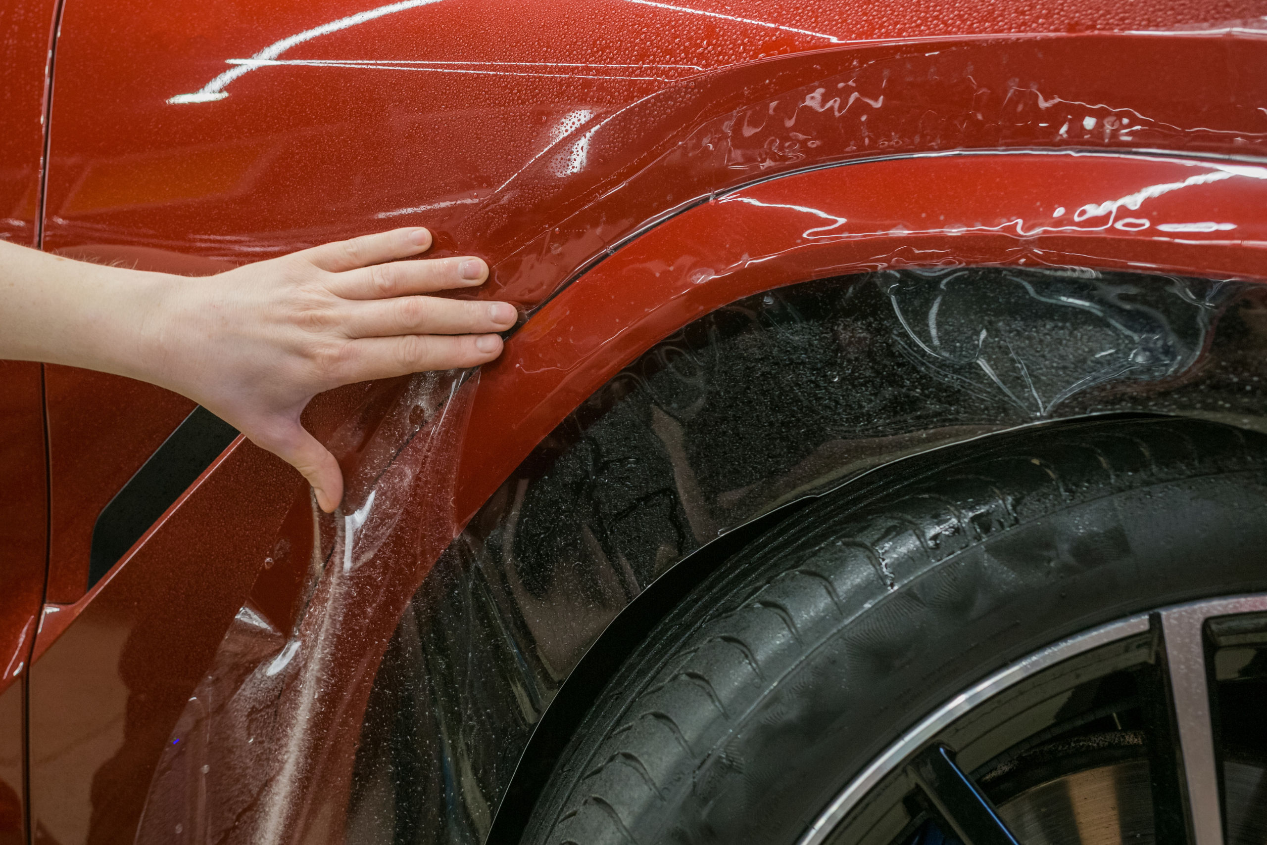 Clear film being applied to a red car.