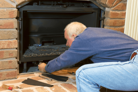 Man taking apart a gas fireplace to maintain it.