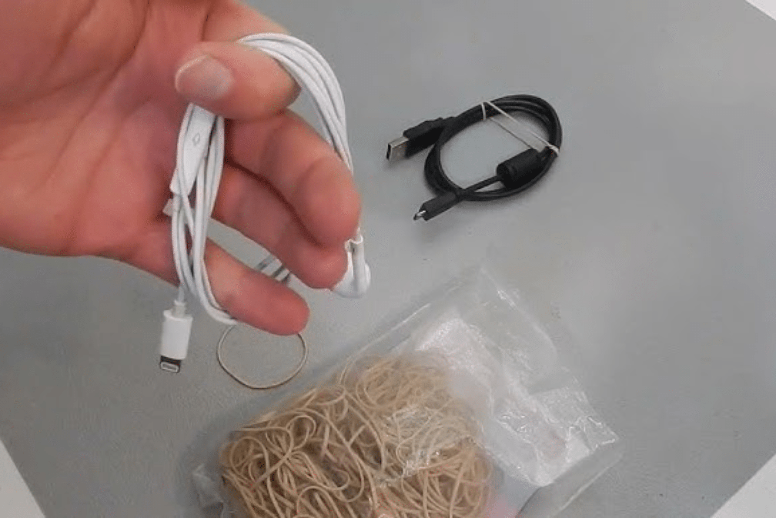 Pack of rubber band on a table with a closeup of a hand holding a pair of earphones.