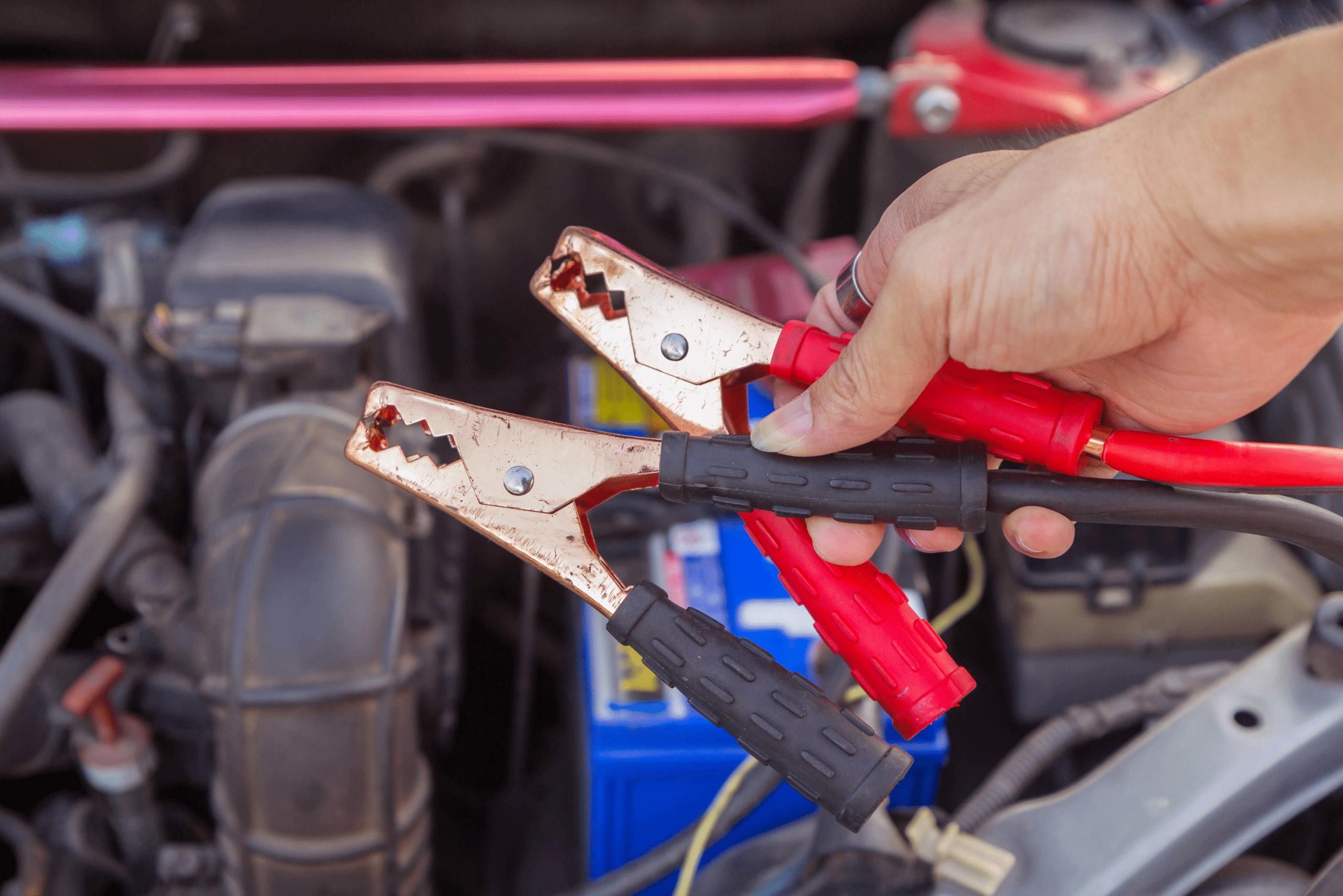 Person holding jumper cable leads.