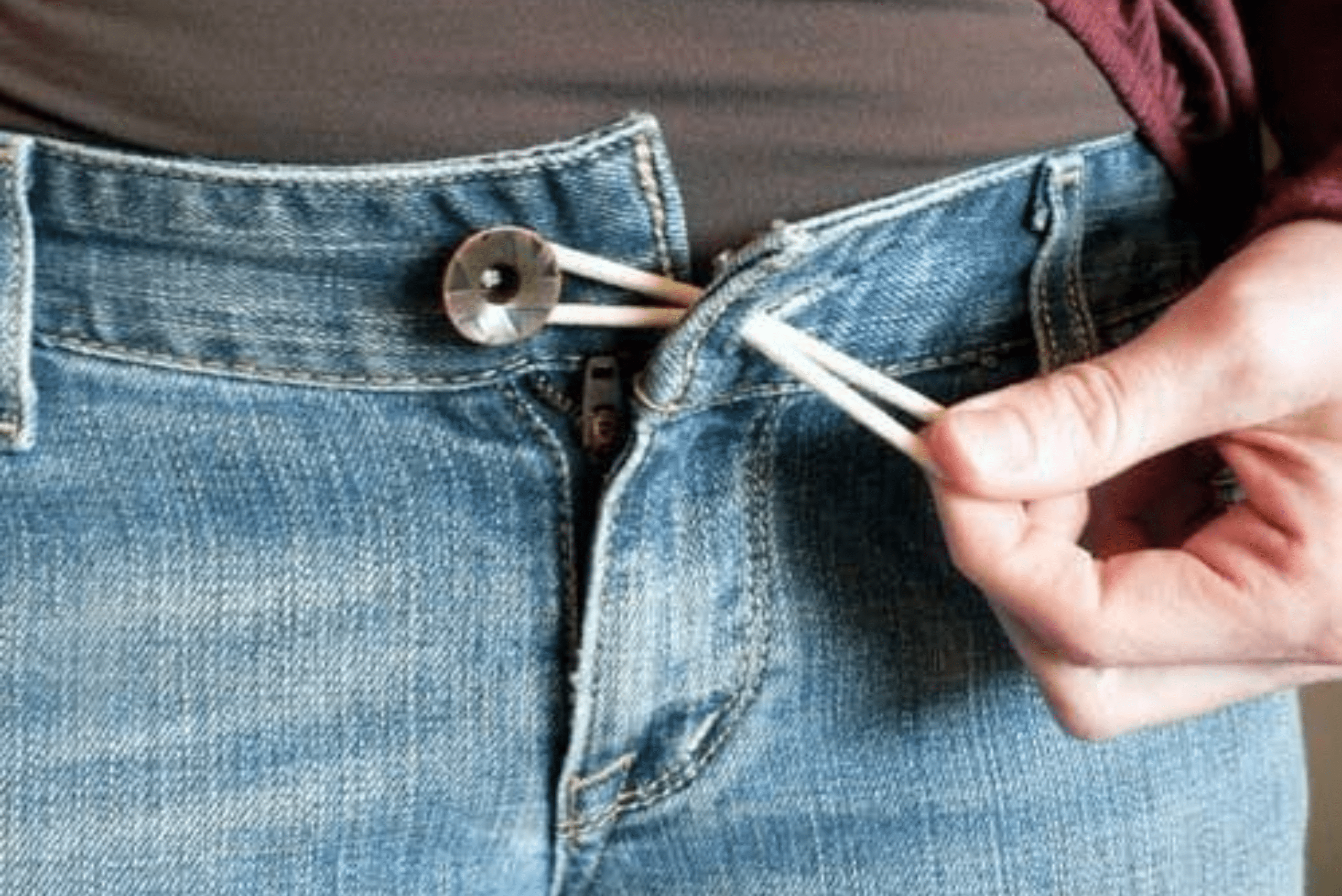 Using rubber band to extend jeans size.