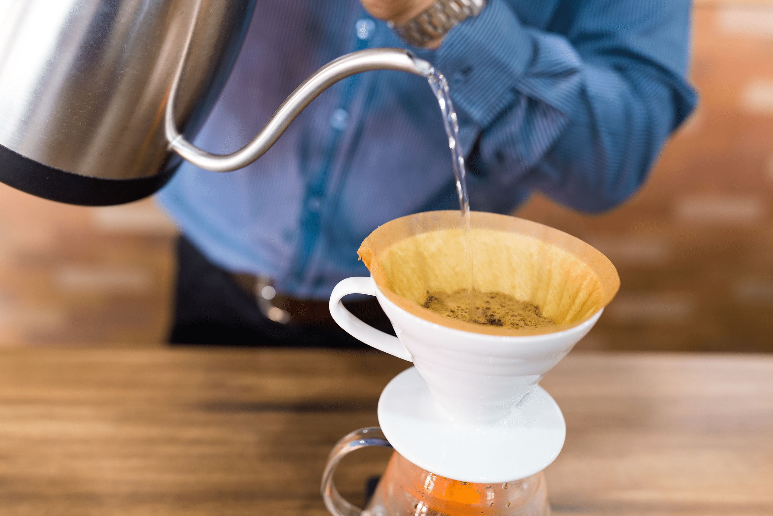 Person making drip coffee using water and a paper filter.