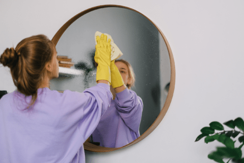 Woman cleaning a mirror.