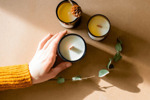 Three candles and someone's hand reaching for one.