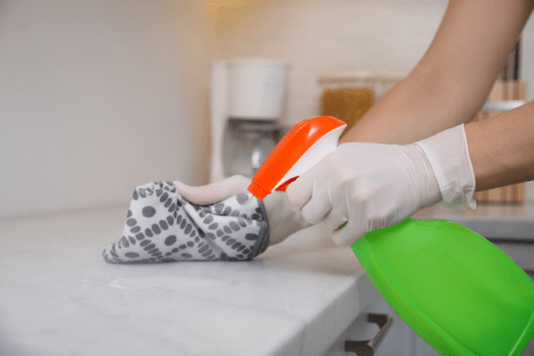 Person cleaning marble countertop with all purpose cleaner.