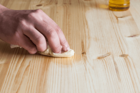 Person rubbing olive oil on wood.