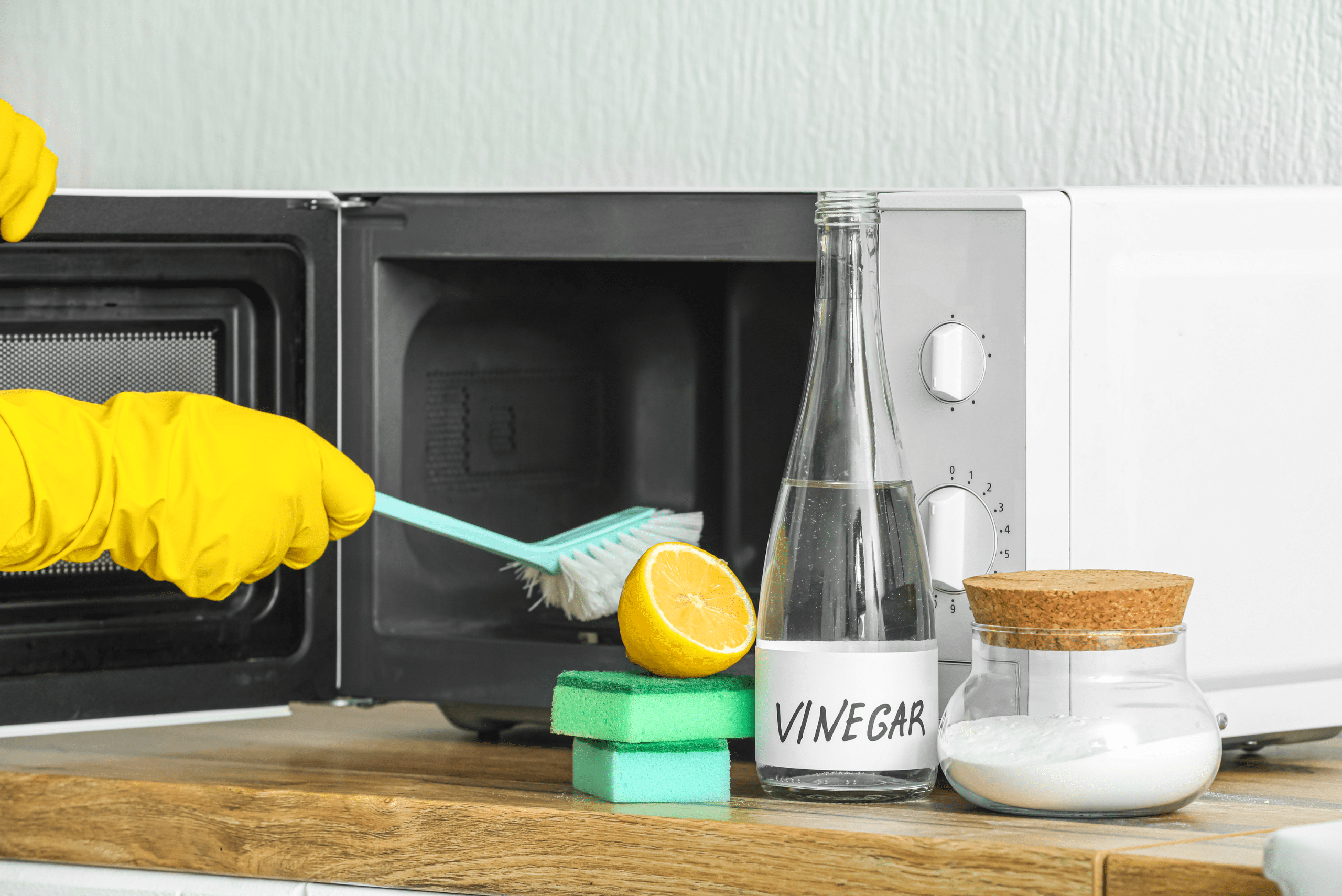 Person scrubbing interior of a microwave.