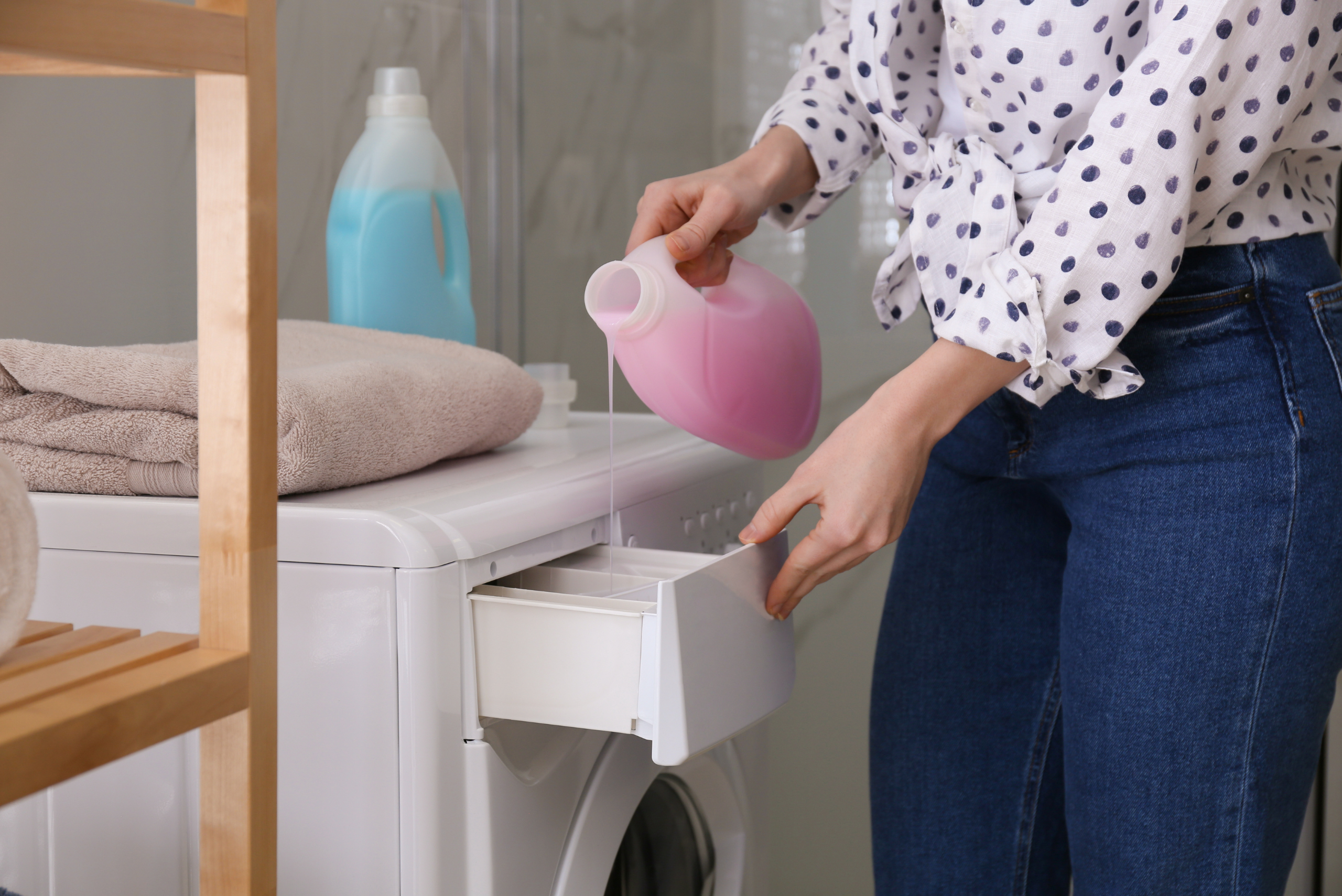 Woman adding detergent to the washing machine.