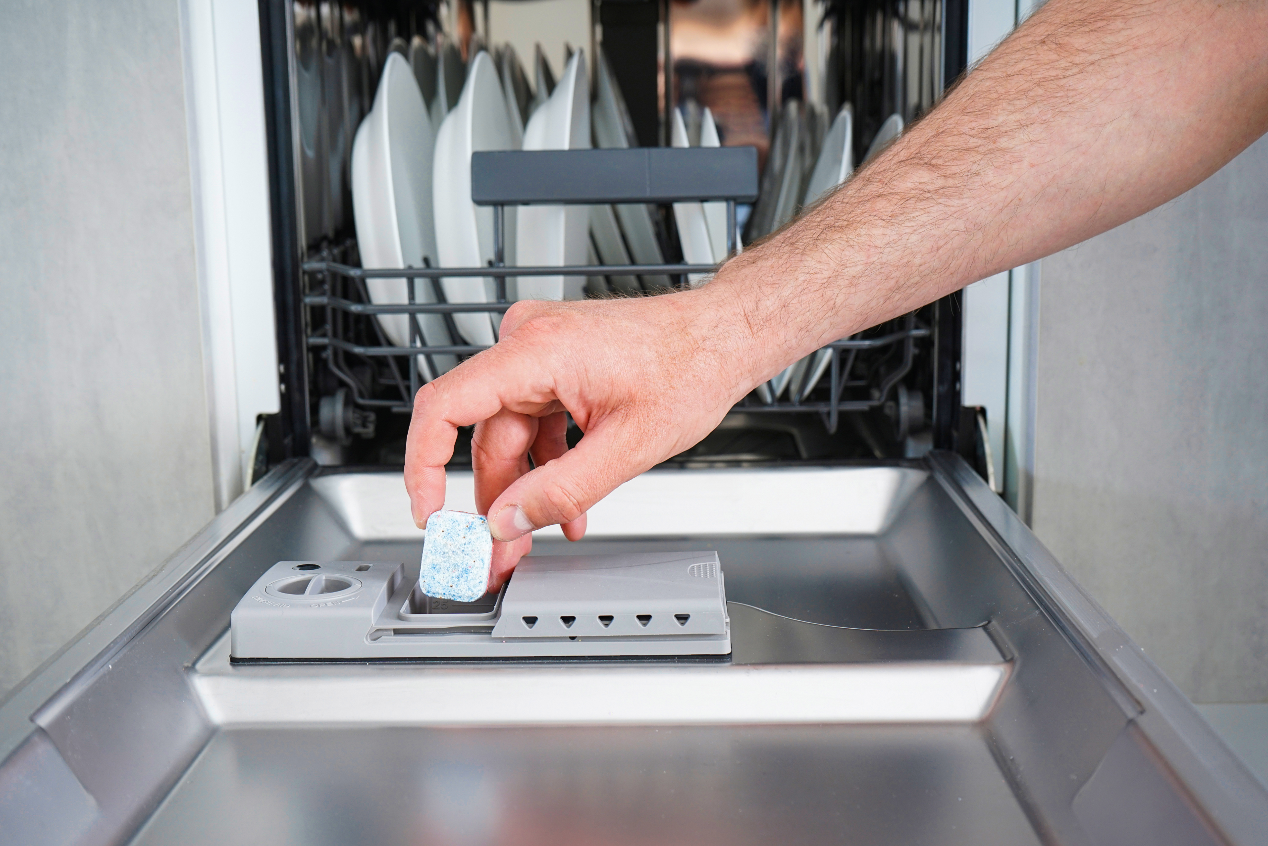 Placing detergent in dishwasher.