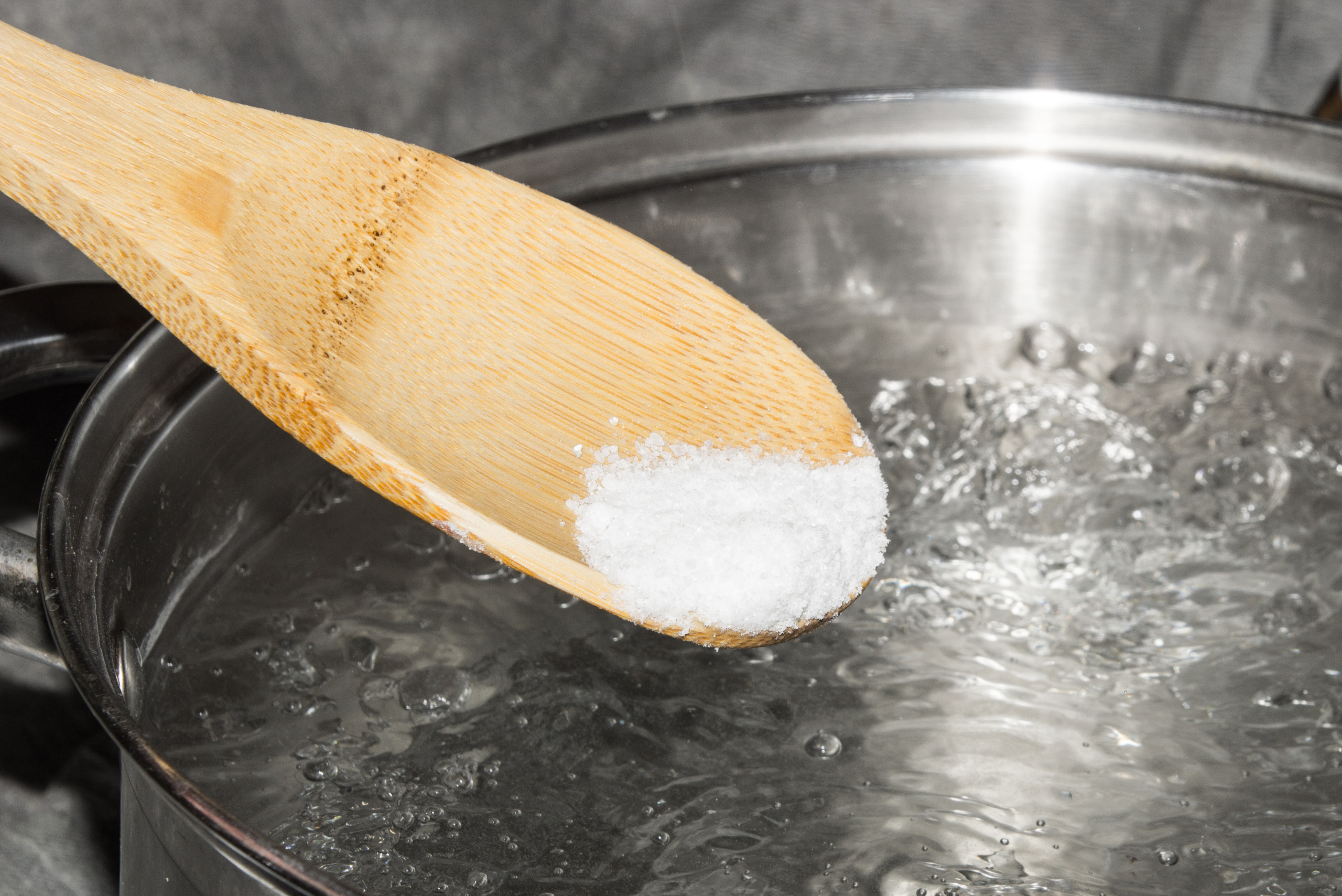 Baking soda on wooden spoon over boiling water.