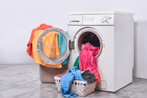 Washing machine full of clothes with door open.