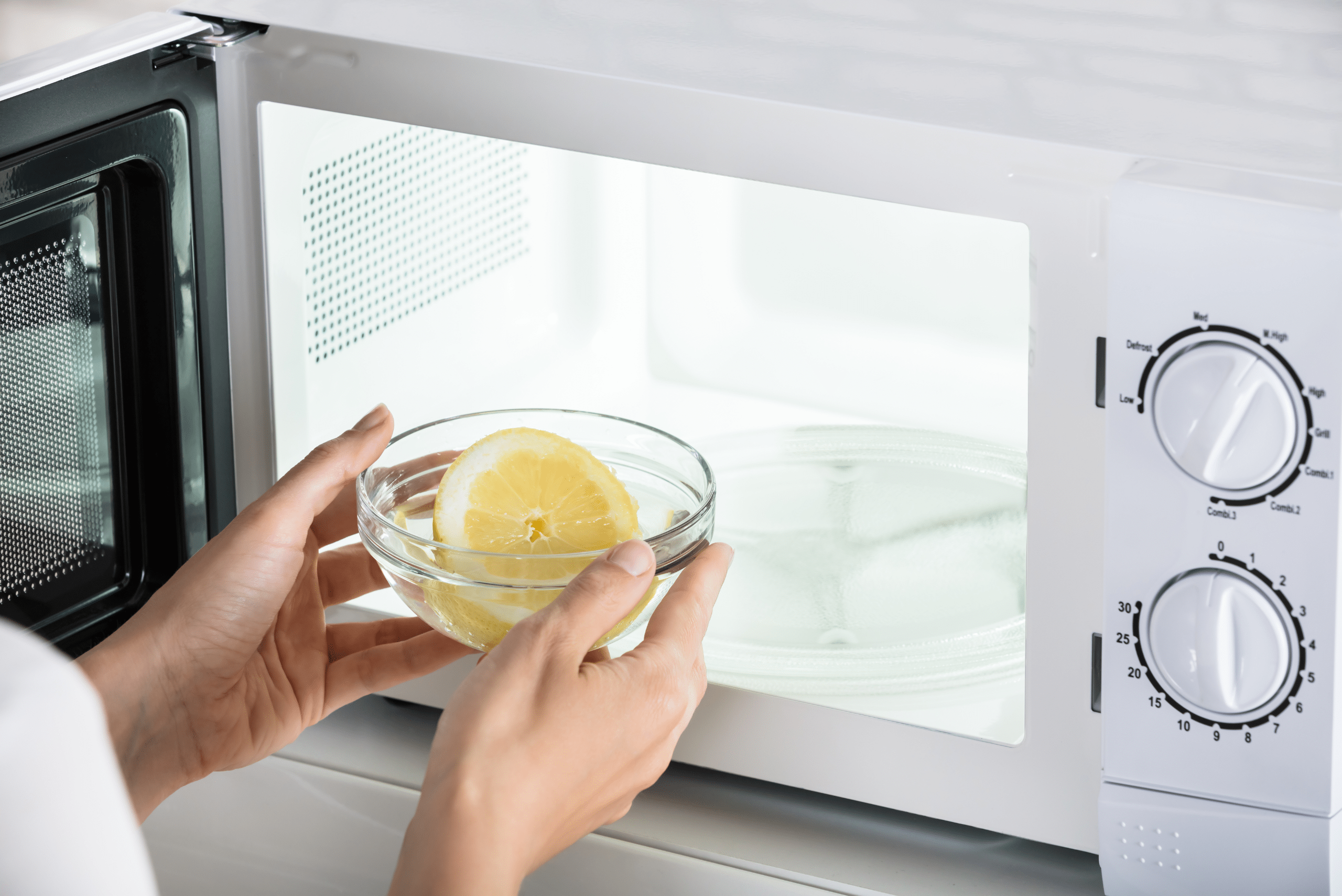 Placing bowl with water and lemon in microwave.