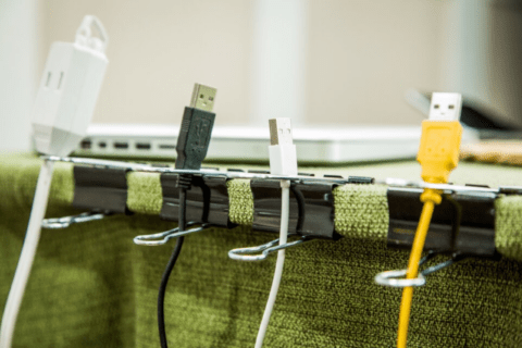 Using binder clips to hold cords on the side of a desk.