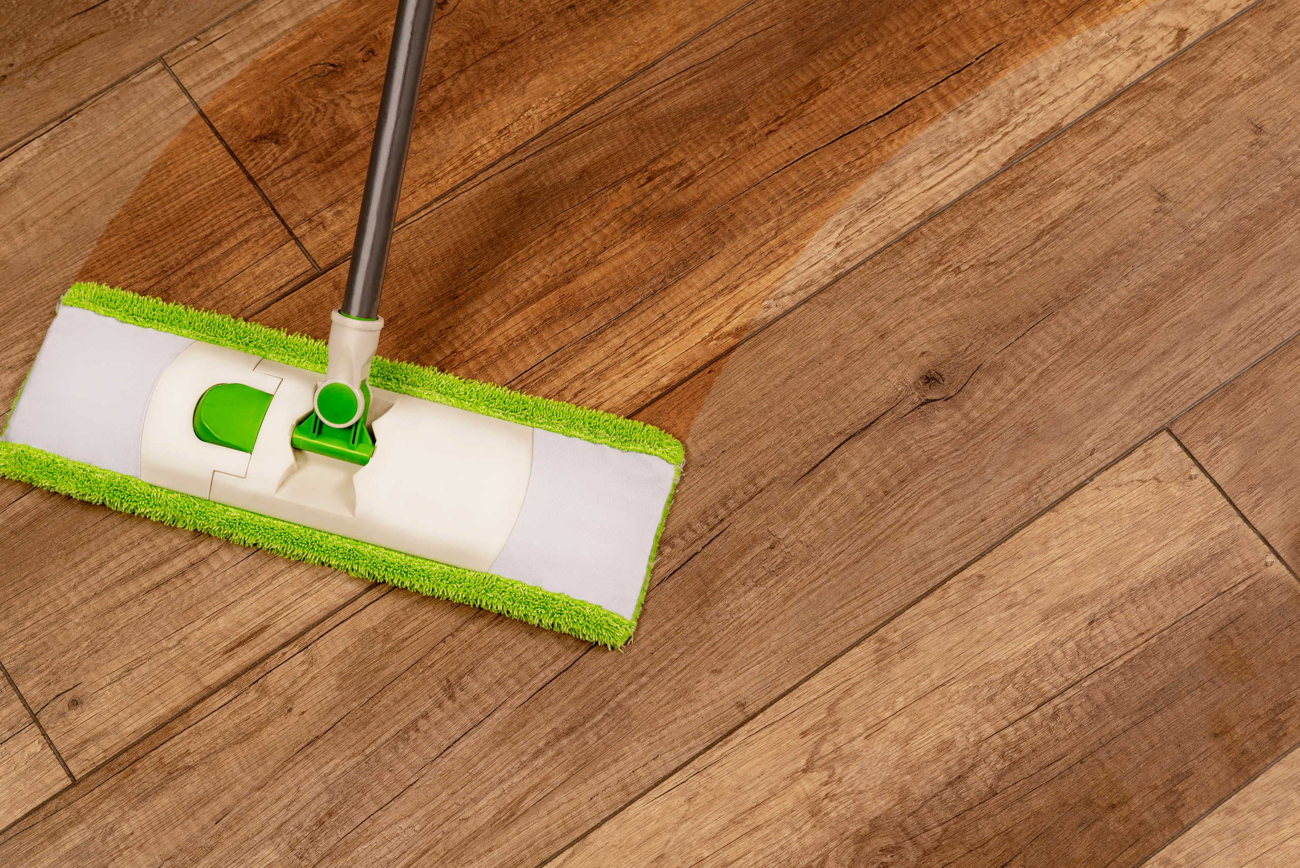 Green flat mop on wood floor.