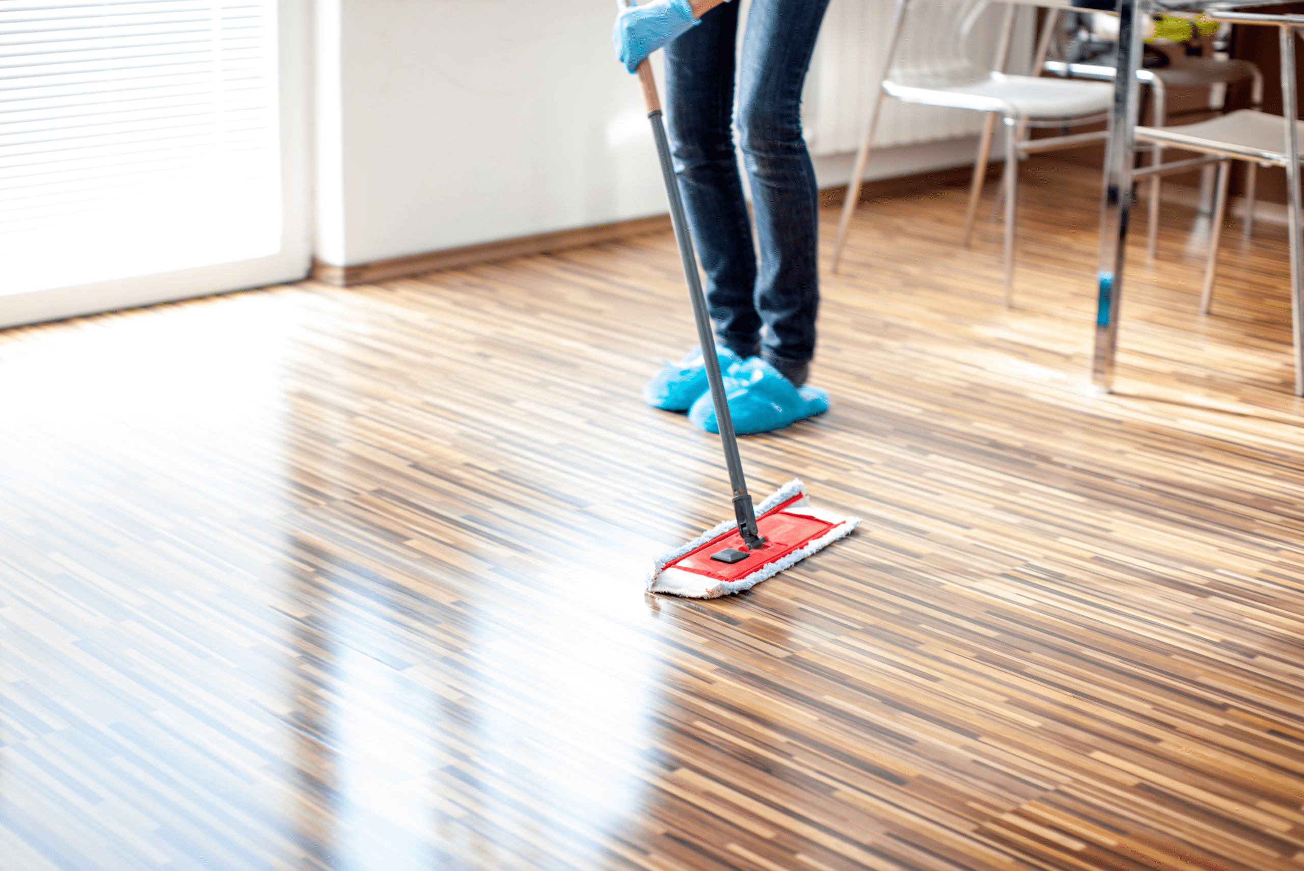 Person mopping wooden floor in a house.