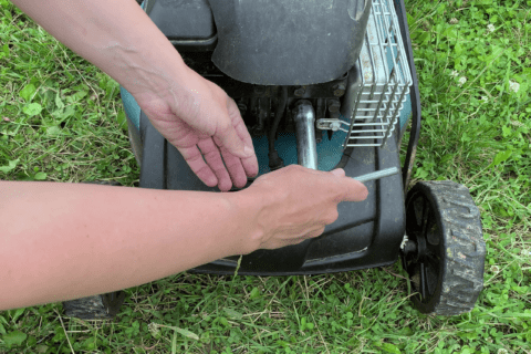 Closeup of someone changing the spark plug of a lawn mower.